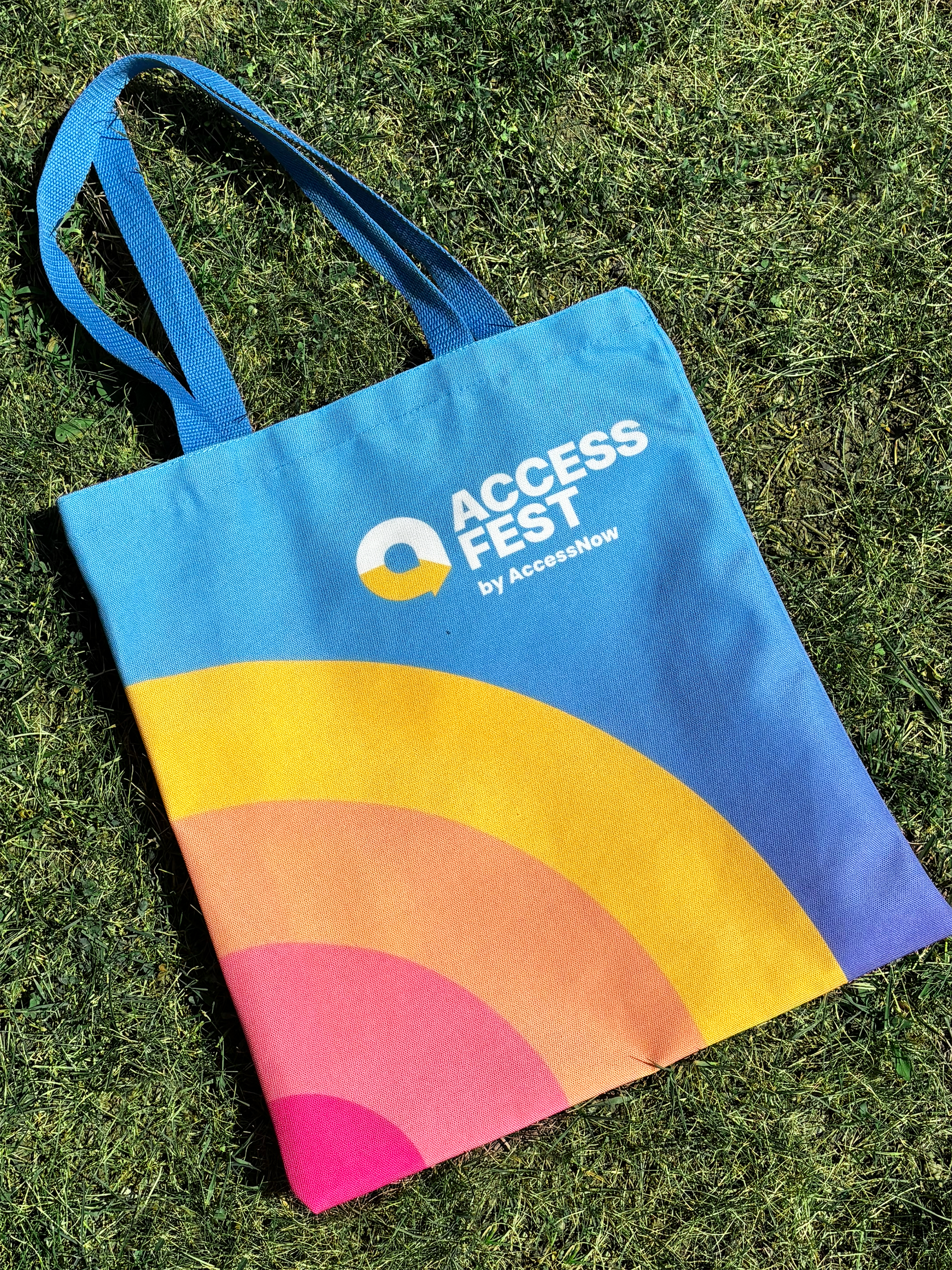 Tote bag with colorful design and 'Access Fest' branding on grass